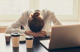 Exhausted woman sleeping at her desk, experiencing OSA symptoms